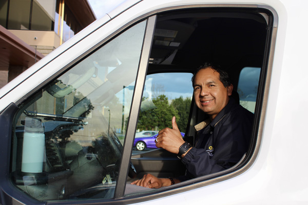 Driver looking out window smiling with a thumbs up for special needs transportation.